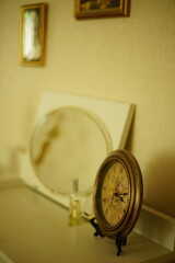 Antique Paris clock on a white vanity table with an oval mirror and paintings on the wall.