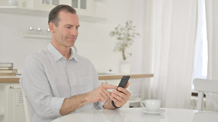 Attractive Middle Aged Man using Smartphone at Home