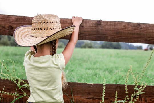 Local vacation, stay safe, stay home. Little girl in cowboy hat playing in western in the farm