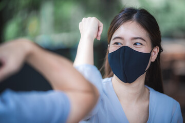 bumping elbows, New novel greeting to avoid the spread of coronavirus. Two people friends meeting with bare hands. Instead of greeting with a handshake, they bump elbows instead.