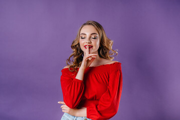 A young beautiful girl shows emotions and smiles in the Studio on a purple background. Girls for advertising