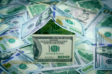 Mortgage crisis concept. House made of dollar bills on a background of green wall