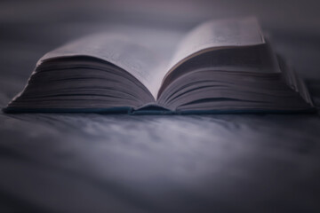 open mystical esoteric book, open on wooden desk in spot of light