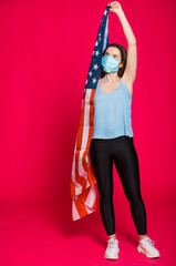 Young woman wearing a face mask with USA flag on red background. Flu epidemic and virus protection concept