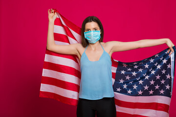Young woman wearing a face mask with USA flag on red background. Flu epidemic and virus protection concept