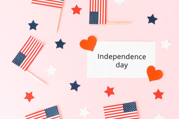 Obraz premium Independence day inscription. Usa flag toothpick, star and heart on pink background, flat lay. Celebration memorial day in America.