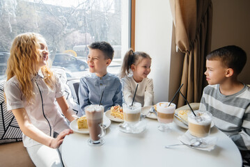 A large friendly company of children celebrate the holiday in a cafe with a delicious dessert. The day of the birth
