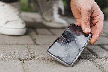 Man hand take broken damaged smartphone from asphalt