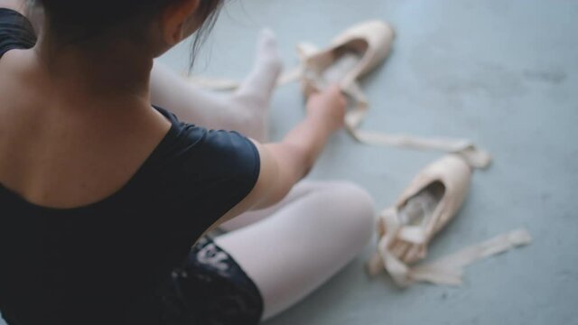 Ballet girl with back view to take off ballet shoes after practice of ballet dance, she look like happy with activity. Concept of little girl practice to increase their ability get more chance life.