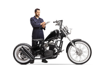 Naklejka na ściany i meble Motorcycle mechanic in a uniform writing a document for a chopper motorbike