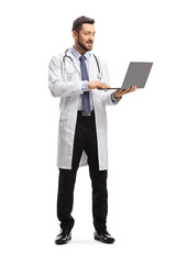 Full length portrait of a male doctor standing and working on a laptop computer