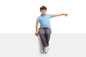 Child sitting on a blank panel and pointing to the side