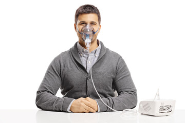 Young man sitting on a table and using an inhalation machine