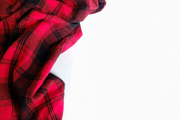Bright red plaid wrinkled shirt on a white background. Environment for working or studying from home. Empty surface surrounded by soft warm material. Cozy home office desk setting for isolation.