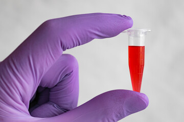 Red sample in a 1.5 ml microcentrifuge tube in gloved hand