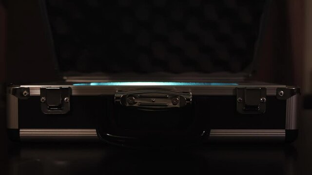 Close up of female hands opening silver metal suitcase with locking system. Concept. Opening aluminum carrying case to find shining mysterious object inside.