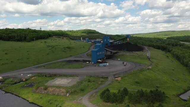 Aerial push in and tilt down showing coal trucks pulling into a coal elevator machine and piles of coal in Mt Storm, WV.