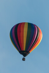 Hot air balloon in rainbow pattern blue sky copy space portrait