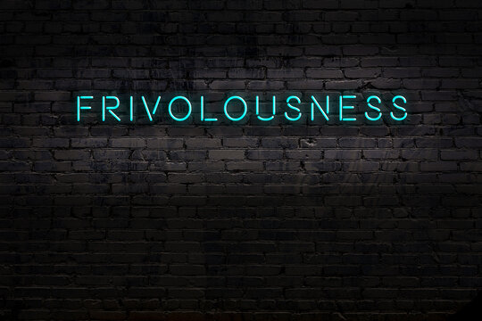Neon sign. Word frivolousness against brick wall. Night view
