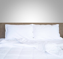 Front view of clean white soft pillows with duvet and bed sheets on the comfortable bed in the bedroom.