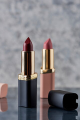 Lápiz labial Rojo con negro y rosa sobre una superficie de mármol con las tapas tiradas al...
