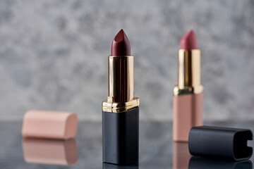 Lápiz labial Rojo con negro y rosa sobre una superficie de mármol con las tapas tiradas al...
