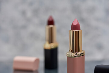 Lápiz labial Rojo con negro y rosa sobre una superficie de mármol con las tapas tiradas al...