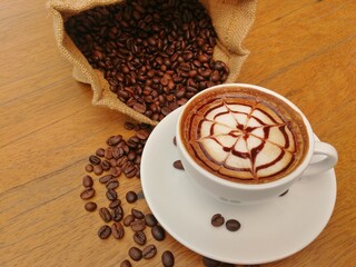 Hot coffee in white cup on able in cafe  with coffee beans in  bag