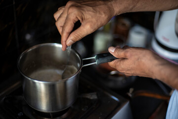 Tea being prepared in a steel tea pot in an Indian kitchen. Indian drink and beverages.