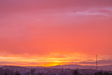 Yellow-red fiery, burning like a flame the evening sky. Beautiful red-yellow sunset over city plans with clouds. All shades of pink in nature