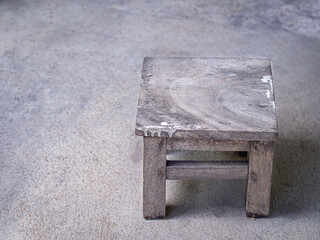 Close-up of vintage wooden stool on concrete floor.