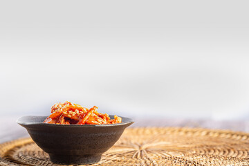 Traditional Korean dishes (Kimchi) in a bowl on rattan pacemat.