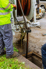 Sewage cleaning workers equipment with sewer on a town street.