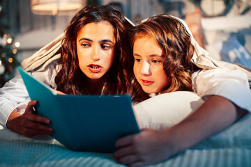 young pretty girls in bed at Christmass morning, happy family smiling lifestyle at holiday reading book