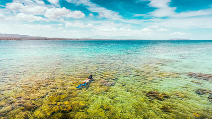 Aerial view of a man snorkeling for treasure in crystal clear water sea in Moyo Island, Sumbawa, Indonesia