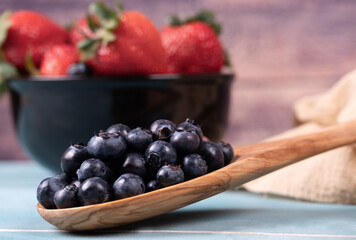 Juicy and fresh organic blueberries on a wooden spoon.
Concept for healthy nutrition.
Close up view.
Tropical fruit  background.