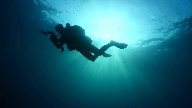 photographer underwater scuba diver with sun beams sun rays and sun shine underwater silhouette man in ocean scenery