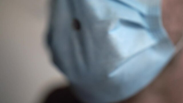 A man leaning forward while smoking through a hole in a face mask