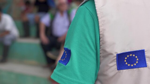 Helping in rural communities. Flag of Europe in volunteer uniform talking.