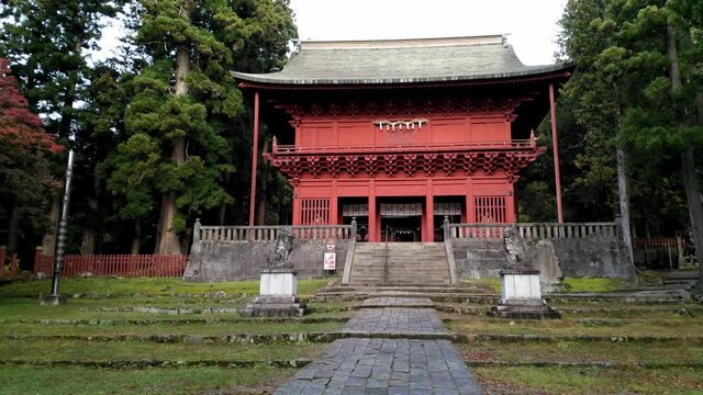 Pan left showing the red entrance gate of buddhist Iwakiyama Shrine in Japan.