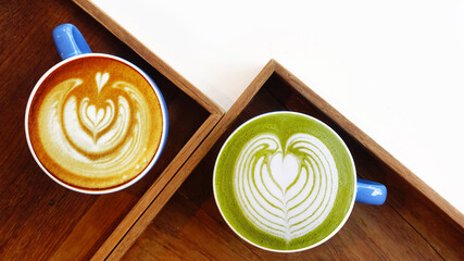 A cup of green tea matcha latte and cup of latte art coffee on wooden background                   ...