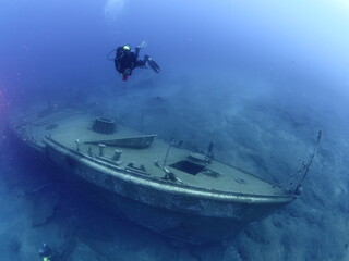 wreck dive underwater fish around ship wreck metal on ocean floor with scuba divers 