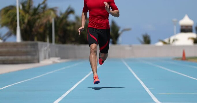 Sprinter runner athlete man sprinting training on outdoor athletics track and field running lanes at stadium. Fitness, sport and health active lifestyle. SLOW MOTION 59.94 FPS.