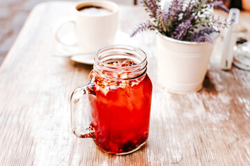 tisane or red herbal tea in a Transparent glass jar on a table outdoors in a tea house in the street