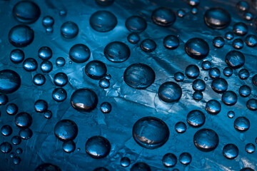 Big turquoise metal spheres are located on a relief turquoise metal surface. Close up.