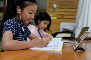 Fototapeta na wymiar Preteen schoolgirl doing her homework with digital tablet at home