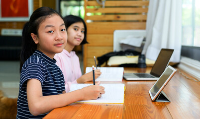 Preteen schoolgirl doing her homework with digital tablet at home