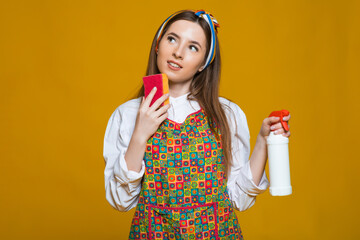 Photo of female houseworker 20s holding colorful duster brush during dusting isolated over yellow background