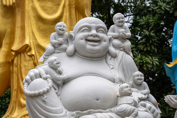 Fototapeta premium Marble sculpture of the happy Buddha with children in a Buddhist temple in the city of Danang, Vietnam