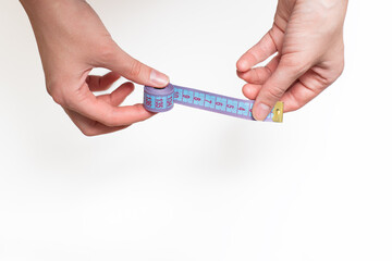 Female hands hold blue roulette, tape measure for measuring size on a light background, copy space